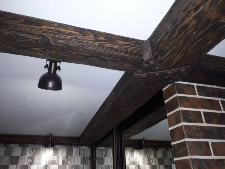 Dark stained beams crossing a white sloped attic ceiling