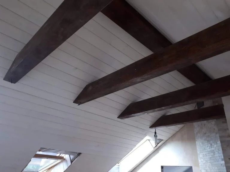 Dark timber beam meeting a white painted ceiling