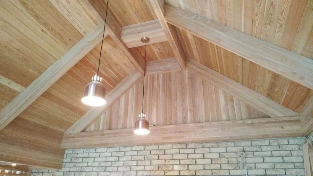 Pale timber roof trusses left exposed above a painted brick wall